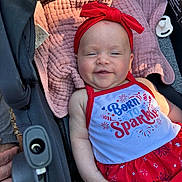 Lennon is registered to the contest to win money with this photo: apparel, baby, babywear, blanket, child, clothing, cute, dress, fabric, happy, headband, infant, outdoor, person, portrait, red, seat, smiling, stroller, white