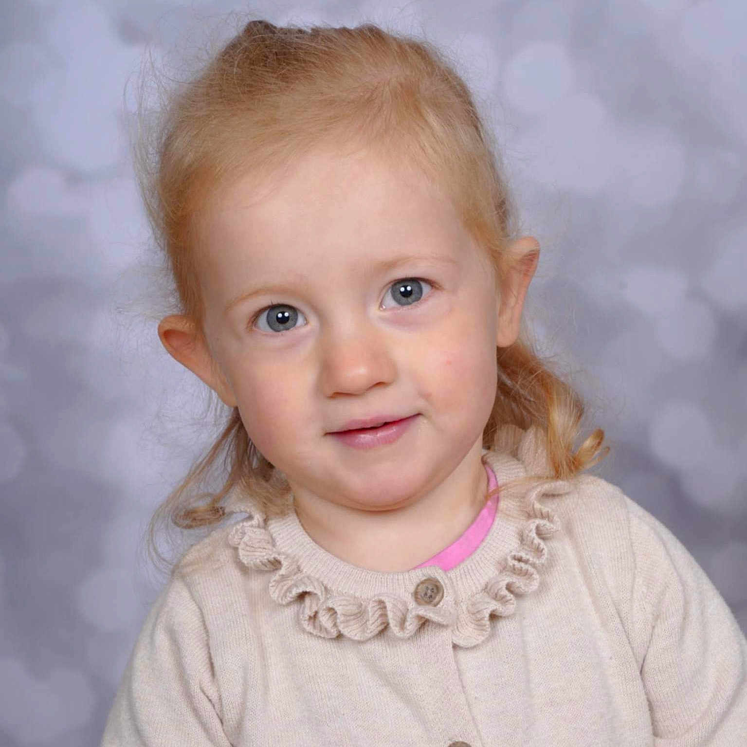 Ellamae is registered to the contest to win money with this photo: background_blur, blonde_hair, blue_eyes, buttoned_sweater, child, closeup, curly_hair, cute, face, fashion, indoor, kid, light, person, portrait, smile, studio, sweater, toddler, young_child