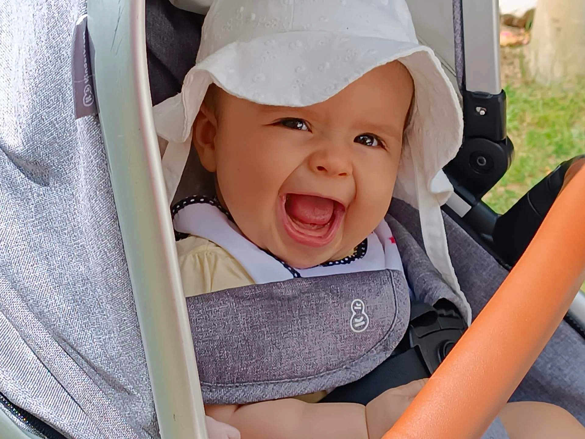 Anna participe au concours pour gagner de l'argent avec cette photo : baby, baby_clothing, baby_seat, child, closeup, cute, daylight, expressive, face, happy, hat, infant, joy, outdoor, person, portrait, seatbelt, smiling, stroller, sunhat