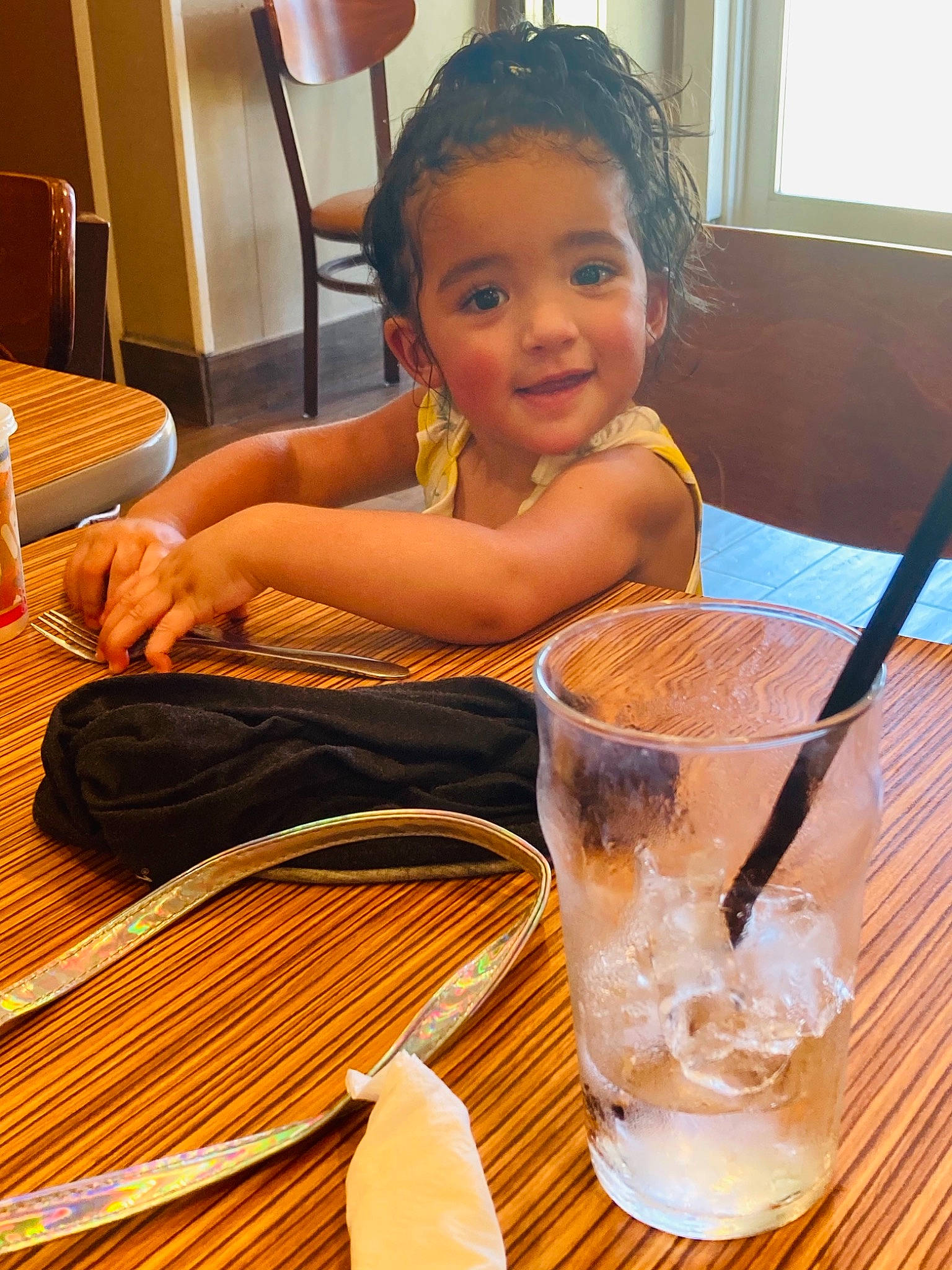 Kayleighn joined the competition — help win amazing prizes! chair, child, cutlery, drinkware, finger, floor, flooring, hardwood, joy, kitchen_utensil, person, plate, room, smile, table, tableware, thumb, toddler, varnish, water