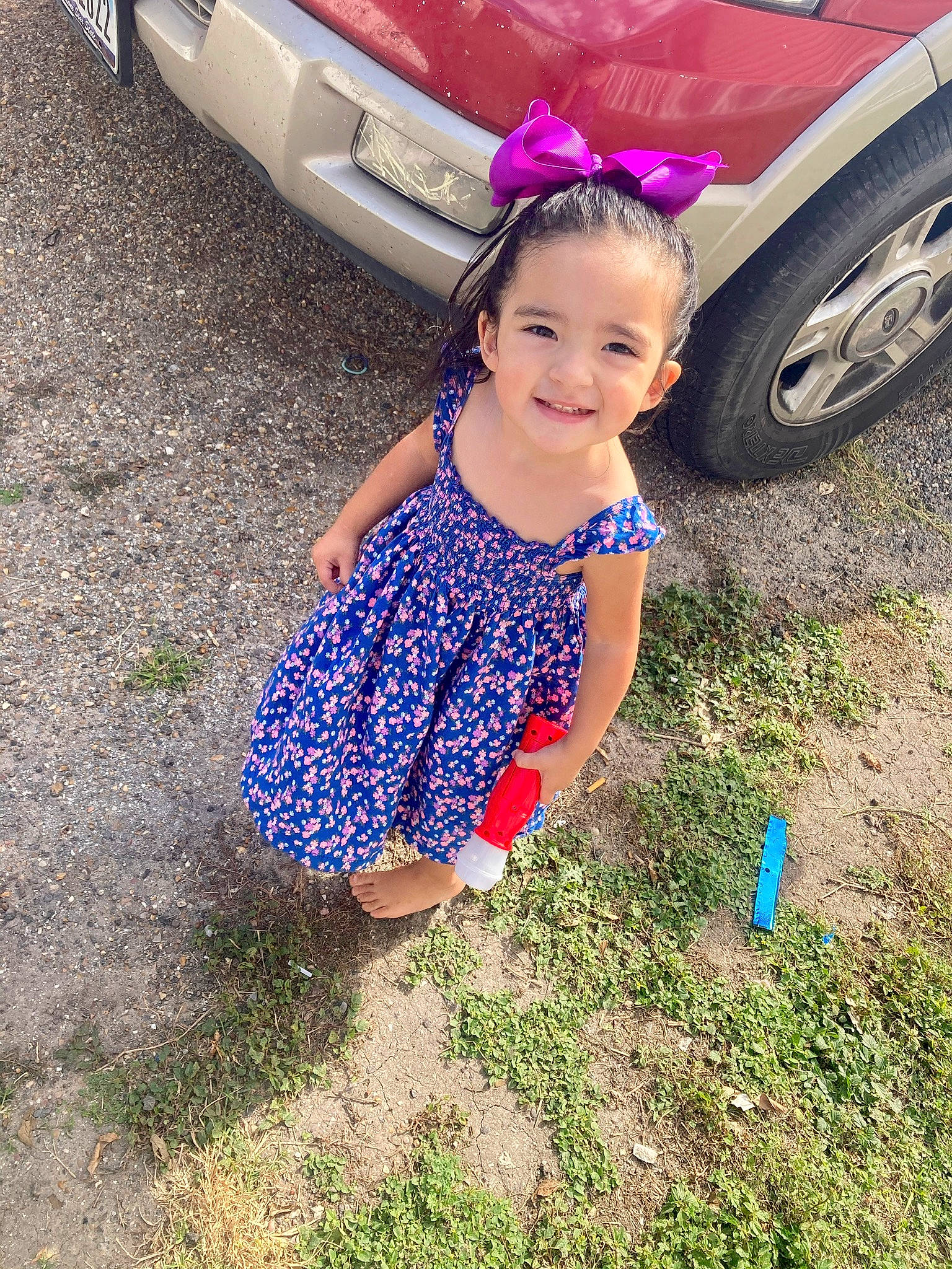 Kayleighn is registered to the contest to win money with this photo: alloy_wheel, automotive_design, automotive_exterior, automotive_lighting, automotive_tire, bumper, car, grass, hand, happy, head, joy, motor_vehicle, people_in_nature, person, rim, smile, tire, toddler, vehicle