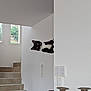 animal, black_and_white, bright, cat, curious, home, indoor, interior, light, minimalistic, mischievous, modern, peeking, pet, playful, stairs, tilted_head, wall, white_wall, window