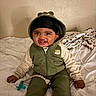 Denim joined the competition — help win amazing prizes! baby, child, smiling, hoodie, green_clothing, pacifier, bed, blanket, indoor, person, cute, happy, sitting, infant, face, headwear, clothing, toy, young_child, portrait