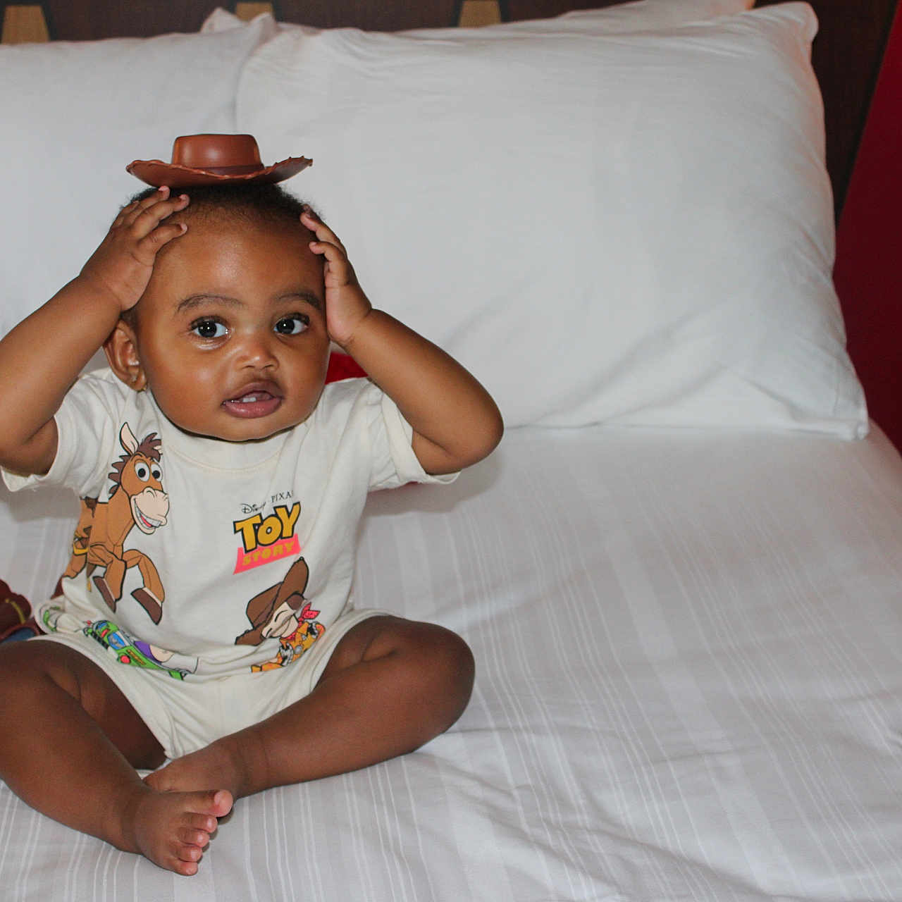 Denim joined the competition — help win amazing prizes! toddler, child, toy_story, cowboy_hat, bed, toys, woody, light, phone, shirt, indoor, playful, smiling, cross-legged, white_bedspread, furniture, lamp, person, cute, young_child