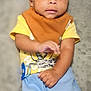 Elias is registered to the contest to win money with this photo: baby, child, infant, yellow_shirt, blue_shorts, brown_bib, pacifier, blanket, soft_texture, indoors, cute, smiling, hands, legs, sitting, portrait, curious, wide_eyes, young_child, comfortable