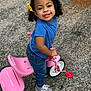 Olive joined the competition — help win amazing prizes! blue_shirt, casual_clothing, child, curly_hair, cute, daylight, happy, jeans, outdoor, pavement, person, pink_tricycle, play, smiling, sneakers, toddler, toy, vehicle, yellow_bow, young_child