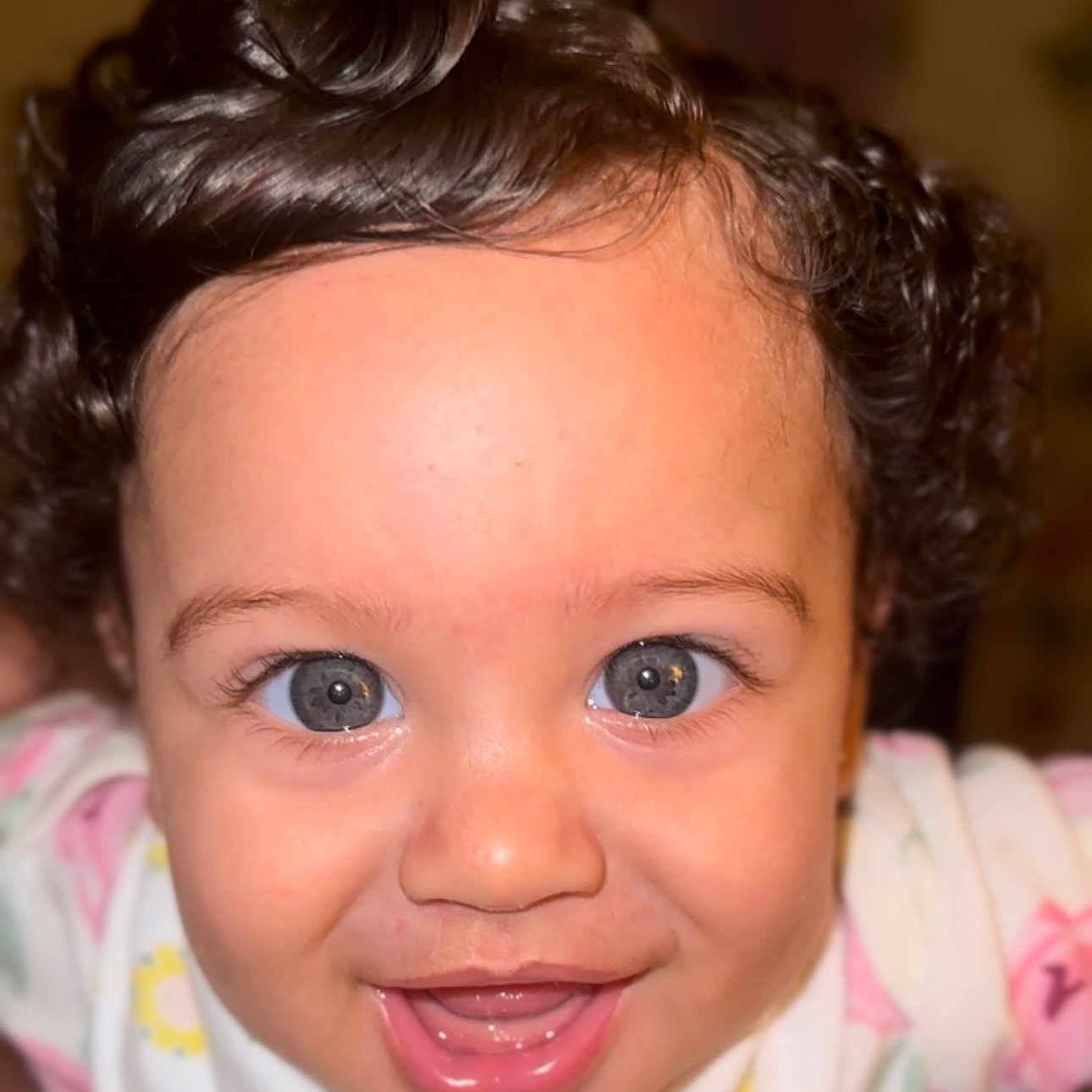 Estelle is registered to the contest to win money with this photo: baby, child, face, smile, blue_eyes, curly_hair, close_up, happy, infant, cute, portrait, young, person, skin, clothing, expression, joy, bright_eyes, indoors, soft_lighting