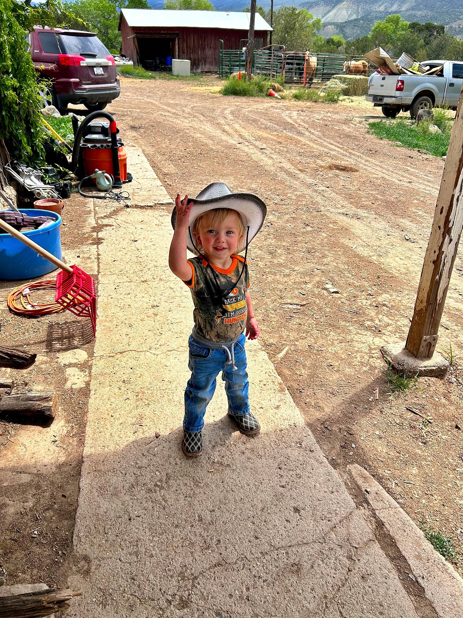 Colton is registered to the contest to win money with this photo: asphalt, car, fun, grass, hat, joy, landscape, leisure, motor_vehicle, person, plant, recreation, road, road_surface, sidewalk, tire, toddler, travel, tree, truck