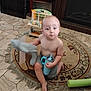 child, toddler, indoor, rug, floor, toy, plush_toy, sippy_cup, barefoot, shorts, person, furniture, wooden, carpet, play, curious, cute, home, floor_tiles, expression