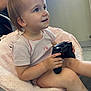 toddler, child, controller, gaming, pink_chair, indoor, happy, casual_clothing, short_sleeve_shirt, bare_legs, floor, window, natural_light, person, smile, curly_hair, tattoo, adult, furniture, relaxed