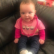 Kinsley is registered to the contest to win money with this photo: baby, infant, child, bib, pink_clothing, jeans, socks, leather_sofa, sitting, portrait, chubby_cheeks, eyes, smile, toy, indoor, candid, cute, cozy, closeup, head