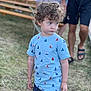 Archie participe au concours pour gagner de l'argent avec cette photo : child, toddler, curly_hair, blue_shirt, sailboat_pattern, shorts, outdoor, grass, picnic_bench, blurred_background, person, summer, casual_clothing, daylight, portrait, standing, thoughtful, event, people, nature