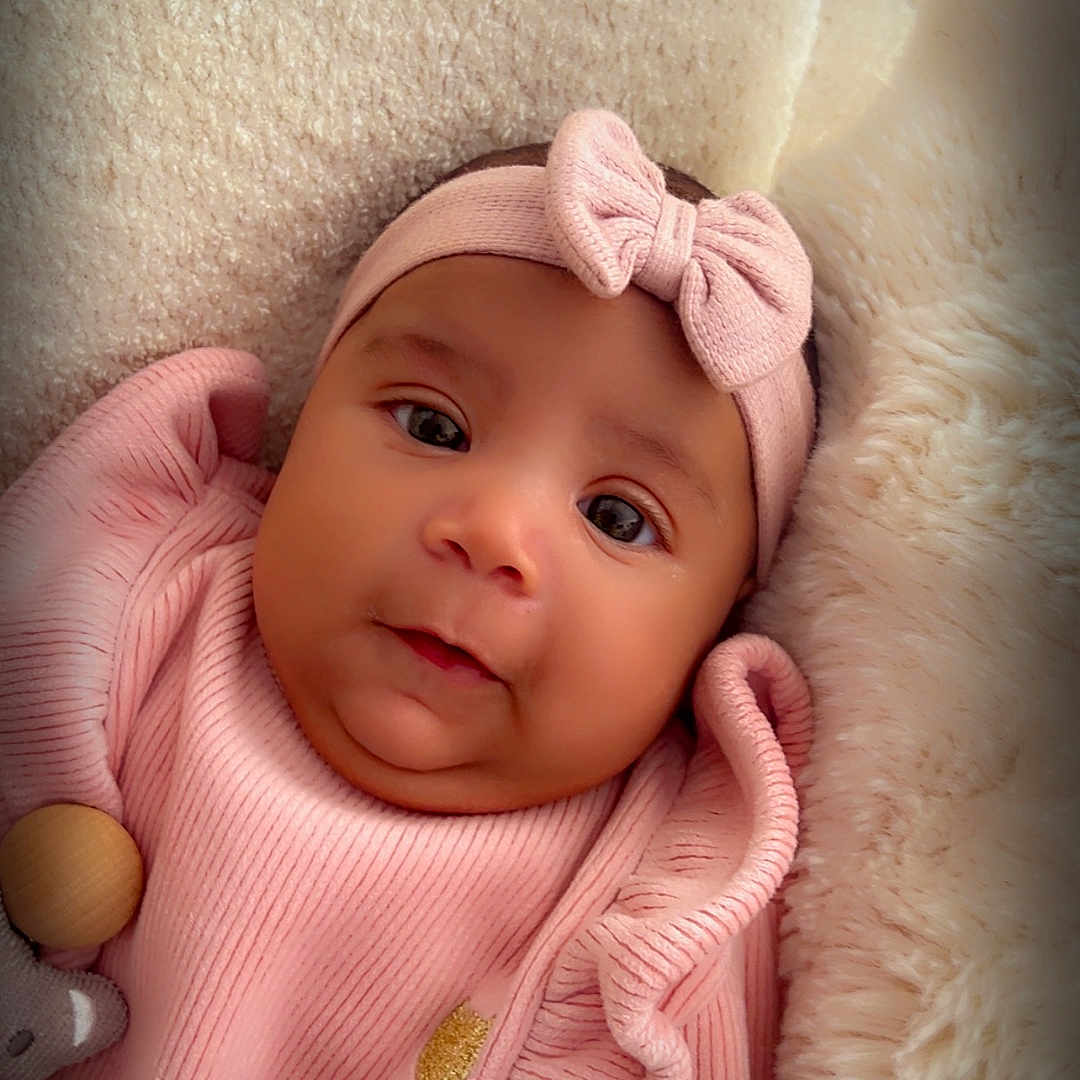 Livia a rejoint le concours — aidez-le/la à gagner de superbes lots ! adorable, baby, blanket, bow, child, closeup, cozy, cute, face, headband, indoors, infant, newborn, pink_clothing, portrait, resting, smile, soft_texture, warm, young