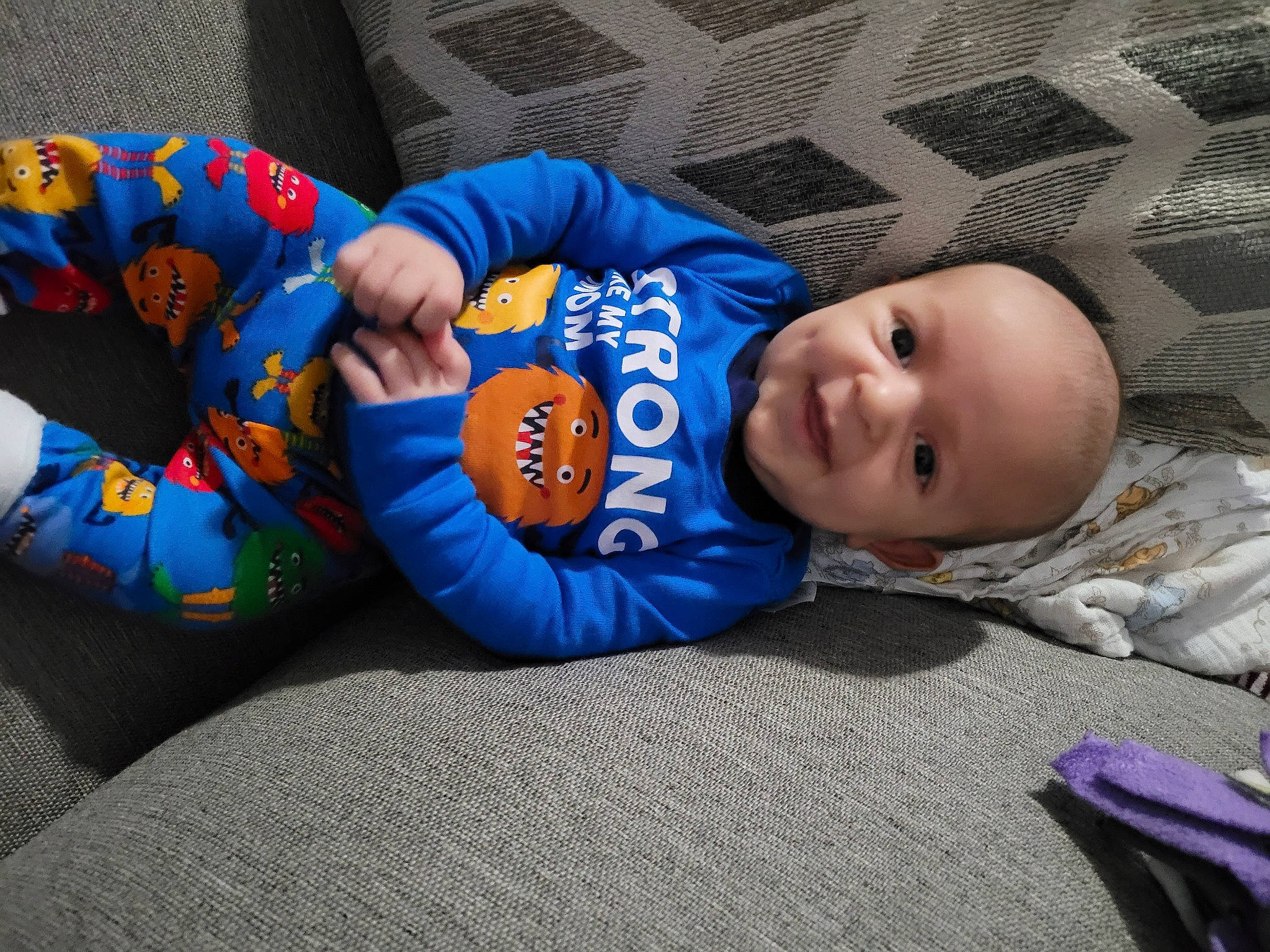 Adam is registered to the contest to win money with this photo: baby, baby_products, baby_toddler_clothing, blue, cheek, child, comfort, couch, electric_blue, eye, flooring, fun, head, human_body, joy, linens, person, sitting, sleeve, smile