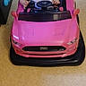 baby, car, carpet, child, cute, expression, face, floor, hands, head, indoor, infant, person, pink, play, seat, steering_wheel, toy_car, vehicle, young_child