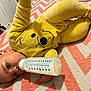 Ezrah is registered to the contest to win money with this photo: baby, bottle, yellow_clothing, onesie, lying_down, milk, face, infant, cheerful, indoors, blanket, pattern, child, cuteness, soft_toys, head, hand, footwear, sleepwear, resting
