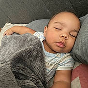 Ezrah is registered to the contest to win money with this photo: baby, sleeping, blanket, couch, pillow, infant, child, cozy, nap, indoors, relaxation, soft_texture, plush, peaceful, comfortable, face, skin, clothing, rest, home