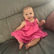 Lola a rejoint le concours — aidez-le/la à gagner de superbes lots ! baby, barefoot, casual, child, couch, cute, face, furniture, happy, home, indoor, infant, person, pink_dress, portrait, seated, sitting, skin, smiling, young
