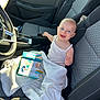 Lola a rejoint le concours — aidez-le/la à gagner de superbes lots ! baby, blanket, blue_eyes, book, car_interior, car_seat, child, cute, front_seat, happy, infant, modern_car, portrait, seatbelt, sitting, smiling, soft_texture, sunlight, toy, white_clothing