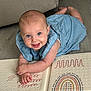baby, blue_eyes, child, colorful, cute, dress, expression, floor, flooring, hand, happy, head, indoors, infant, lying_down, person, play_mat, skin, smile, young_child