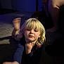 child, blonde_hair, carpet, indoor, reaching, person, childhood, face, portrait, curious, casual, shadow, dog, adult, legs, blue_clothing, home, floor, lighting, expression