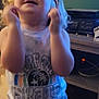 Hunter is registered to the contest to win money with this photo: toddler, child, glasses, indoor, blonde_hair, shirt, shorts, wooden_floor, furniture, shelf, toy, playful, smiling, person, cute, home, young_child, standing, colorful, casual_clothing