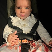 Isalys Monnier a rejoint le concours — aidez-le/la à gagner de superbes lots ! baby, child, car_seat, seatbelt, clothing, white_top, floral_skirt, face, hands, sitting, infant, young_child, cute, indoor, portrait, straps, safety, expression, looking_at_camera, person