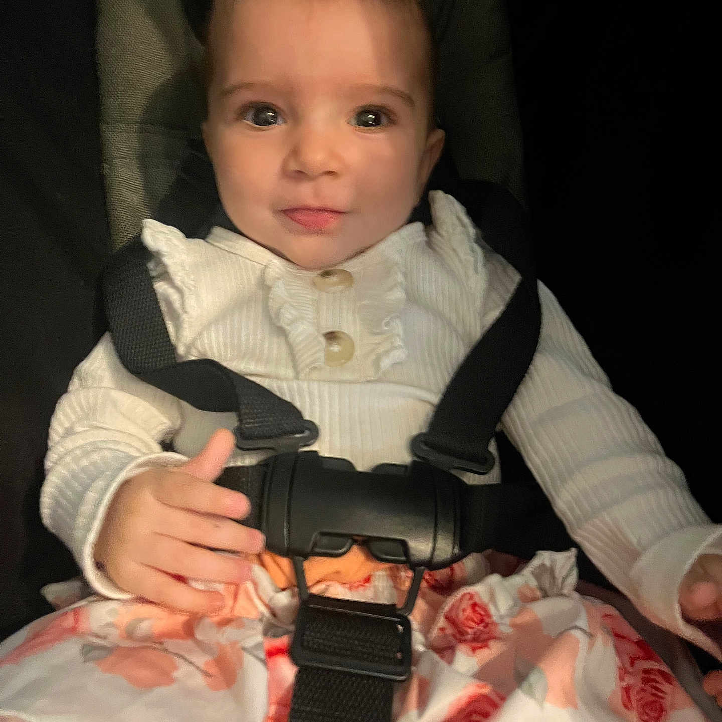 Isalys Monnier a rejoint le concours — aidez-le/la à gagner de superbes lots ! baby, car_seat, child, clothing, cute, expression, face, floral_skirt, hands, indoor, infant, looking_at_camera, person, portrait, safety, seatbelt, sitting, straps, white_top, young_child