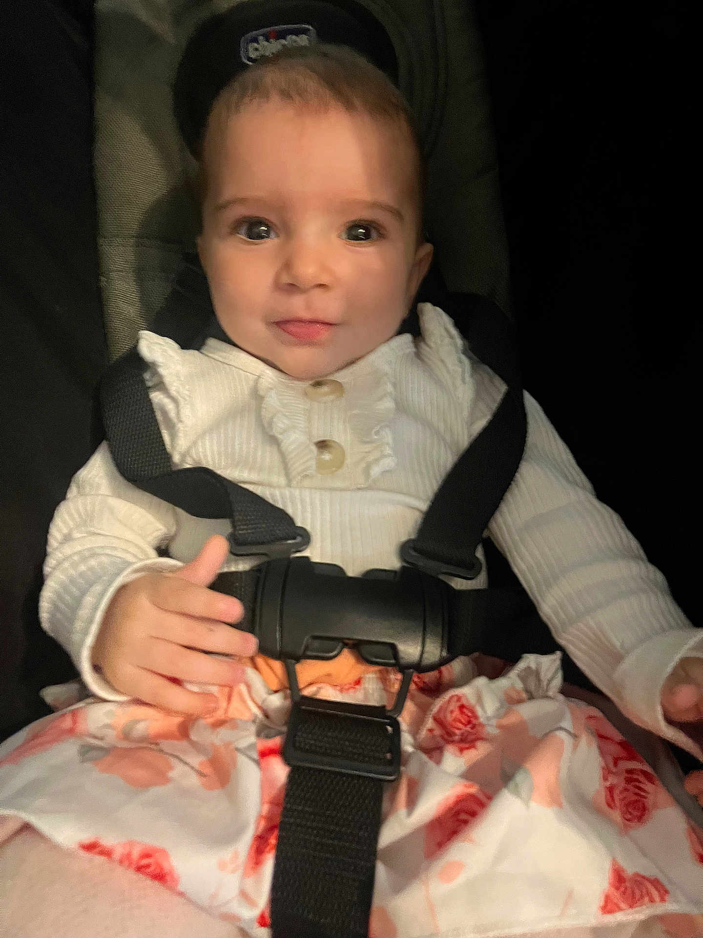Isalys Monnier a rejoint le concours — aidez-le/la à gagner de superbes lots ! baby, child, car_seat, seatbelt, clothing, white_top, floral_skirt, face, hands, sitting, infant, young_child, cute, indoor, portrait, straps, safety, expression, looking_at_camera, person