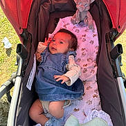 Araceli is registered to the contest to win money with this photo: baby, stroller, denim_dress, plush_toy, elephant_toy, blanket, socks, infant, outdoor, sunlight, grass, curious, child, clothing, soft_toy, baby_blanket, cute, portrait, young_child, resting