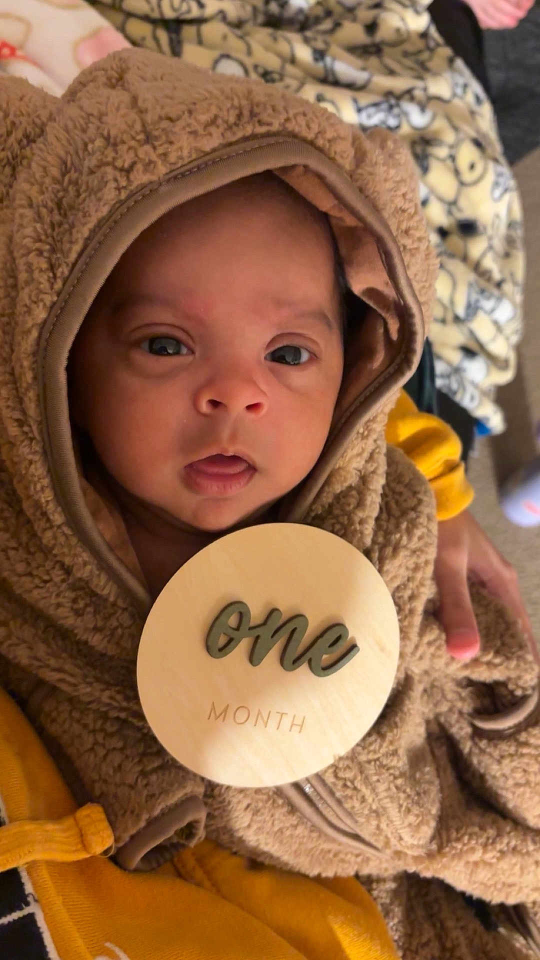 Miguel joined the competition — help win amazing prizes! baby, infant, hoodie, brown, plaque, one_month, cozy, fuzzy, cute, portrait, child, newborn, hand, fabric, clothing, face, eyes, indoor, person, milestone