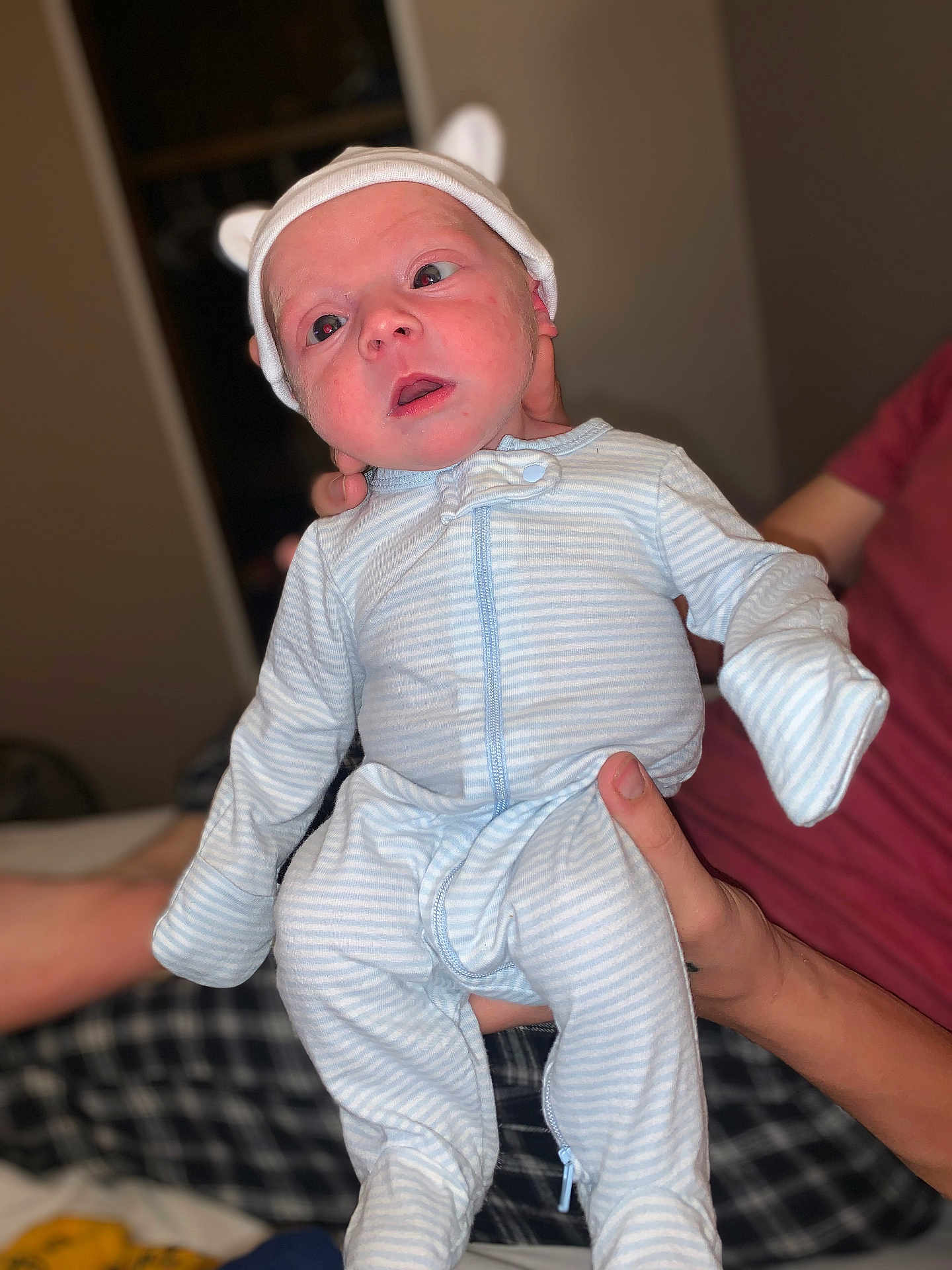 Finnegan joined the competition — help win amazing prizes! baby, infant, child, onesie, hat, ears, human_hand, person, indoor, portrait, cute, sleepwear, striped_clothing, newborn, expression, holding, soft_lighting, blurred_background, young, curious