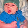 Finnegan joined the competition — help win amazing prizes! baby, infant, child, blue_onesie, green_hat, dinosaur_logo, tongue_out, lying_down, soft_background, cute, playful, newborn, hand, face, skin, clothing, indoors, portrait, headwear, expression