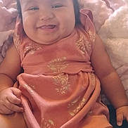 Kauionalani is registered to the contest to win money with this photo: baby, child, smiling, pink_dress, bow, blanket, plush, cute, happy, infant, sitting, indoors, soft_toys, diaper, portrait, chubby_cheeks, young_child, person, face, cozy