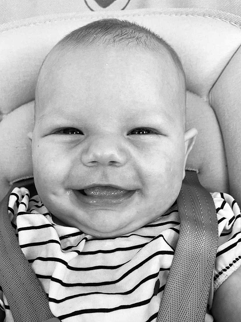 Capucine participe au concours pour gagner de l'argent avec cette photo : baby, smile, face, child, striped_shirt, car_seat, seatbelt, happy, infant, closeup, portrait, cute, black_and_white, apparel, person, young_child, head, expression, sitting, joyful
