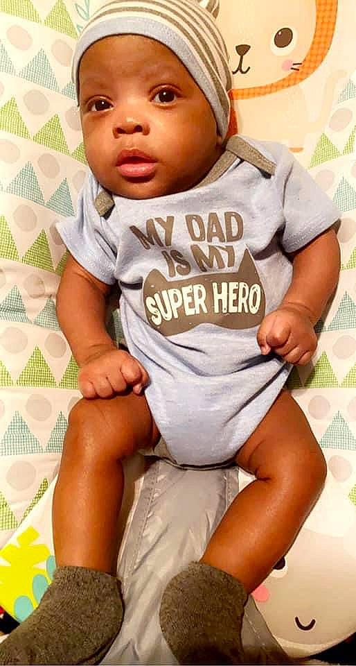Jamari joined the competition — help win amazing prizes! baby, baby_toddler_clothing, black, cheek, child, comfort, finger, gesture, happy, headwear, jersey, orange, person, sitting, skin, sleeve, sock, t_shirt, thigh, thumb