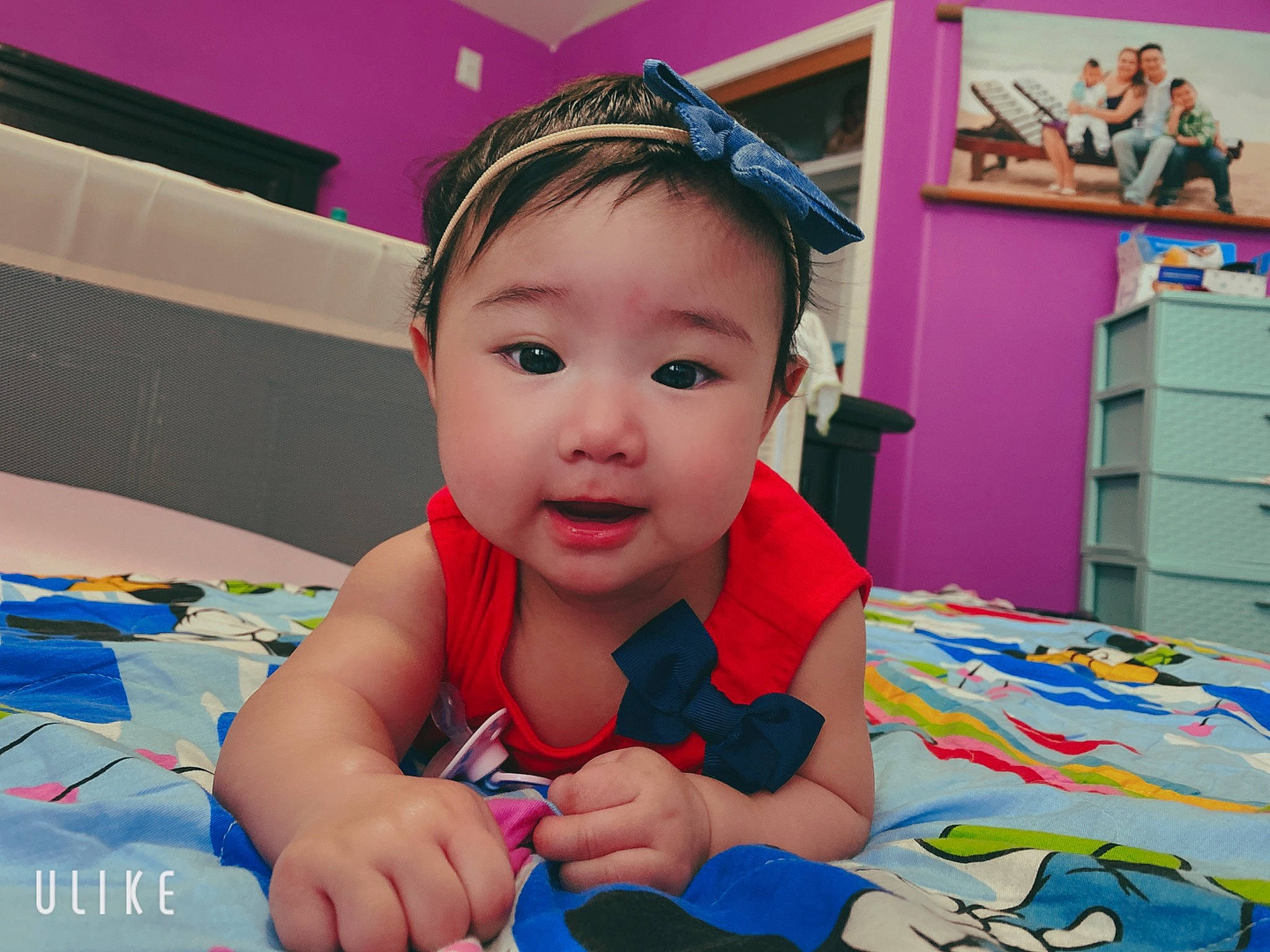 Holly is registered to the contest to win money with this photo: baby, baby_products, baby_toddler_clothing, blurred, cheek, child, finger, fun, hair_accessory, head, headband, leisure, person, play, product, room, smile, toddler, toy, tummy_time