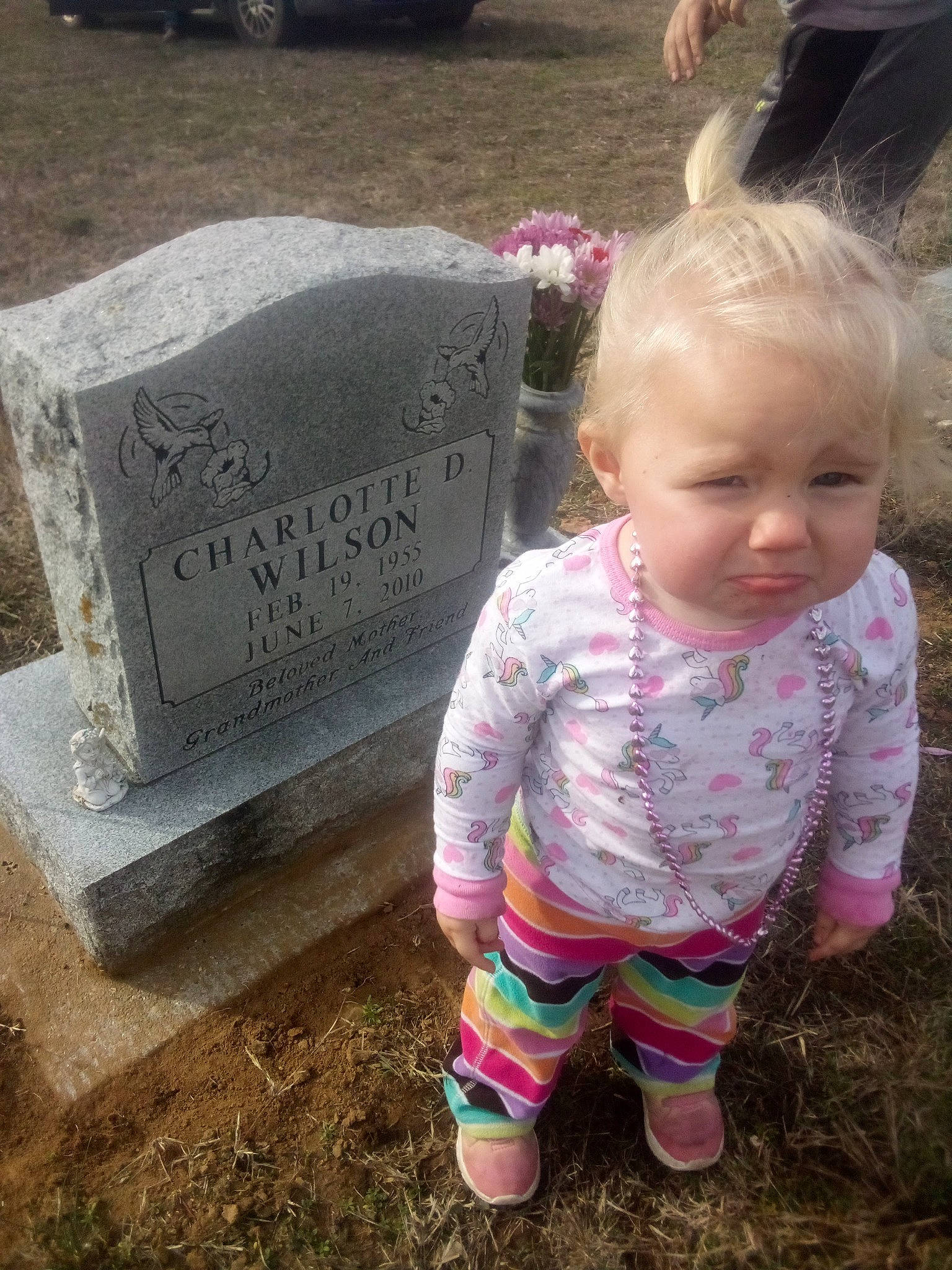 Ariana is registered to the contest to win money with this photo: baby, baby_toddler_clothing, cemetery, child, concrete, font, fun, grass, grave, happy, headstone, pattern, people_in_nature, person, pink, sitting, sleeve, soil, sorrow, tire
