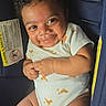 Kevin is registered to the contest to win money with this photo: baby, infant, smiling, curly_hair, onesie, car_seat, child, cute, happy, skin, cheeks, seatbelt, clothing, indoors, person, portrait, young_child, sitting, baby_girl, baby_boy