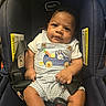 Kevin joined the competition — help win amazing prizes! baby, child, car_seat, overalls, striped_clothing, bunny_design, carrot_design, curly_hair, infant, sitting, cute, portrait, indoor, clothing, seatbelt, safety, young_child, looking_at_camera, small_hands, expression