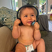 Gabin a rejoint le concours — aidez-le/la à gagner de superbes lots ! baby, diaper, headphones, pacifier, couch, child, indoor, happy, curious, sitting, living_room, pillow, toy, window, natural_light, skin, furniture, person, infant, home