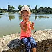 Rinèd participe au concours pour gagner de l'argent avec cette photo : blue_sky, casual_clothing, child, daytime, gesture, girl, hat, lake, leggings, nature, outdoor, pink_shoes, portrait, sitting, stone_wall, summer, sunny, trees, water, young