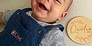 Fabio a rejoint le concours — aidez-le/la à gagner de superbes lots ! baby, smiling, striped_shirt, blue_overalls, face, child, infant, happy, lying_down, wooden_plaque, textile_surface, cute, portrait, young_child, expressive_face, closeup, one_person, indoors, soft_lighting, casual_clothing