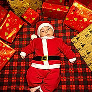 Bastien participe au concours pour gagner de l'argent avec cette photo : baby, celebration, child, christmas, cute, festive, gift_wrap, hat, holiday, holiday_decor, indoor, infant, plaid_blanket, presents, red_clothing, santa_costume, seasonal, small_feet, smiling, wrapped_gifts