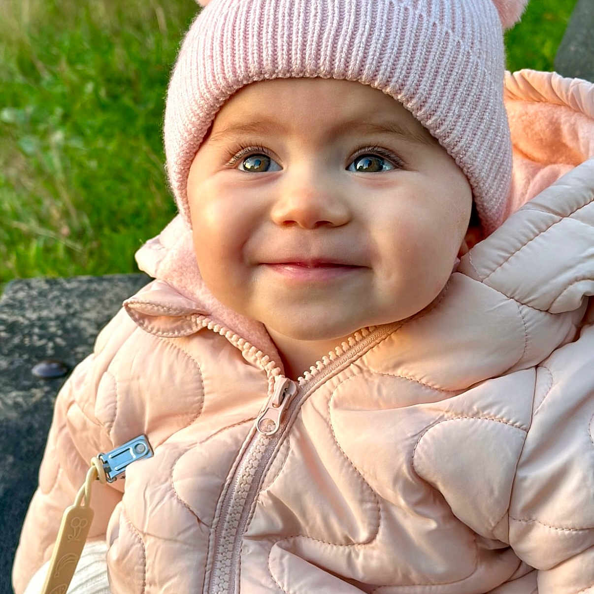 Amelia joined the competition — help win amazing prizes! baby, baby_jacket, child, closeup, cute, eyes, faces, green_background, happy, infant, knit_hat, nature, outdoor, pink_hat, pom_poms, portrait, quilted_jacket, smile, warm_clothing, winter_wear