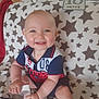 baby, blanket, cheerful, child, clothing, door, face, footwear, hand, happy, indoor, infant, polo_shirt, red_blanket, room, shorts, sitting, smiling, star_pattern, toy