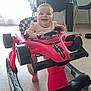 baby, child, toy_car, walker, smiling, indoor, floor, table, chair, bottle, happy, person, foot, plastic, playtime, furniture, daylight, cute, young_child, home