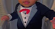 Jaxxon is registered to the contest to win money with this photo: adorable, baby, baby_boy, child, clothing, curly_hair, cute, cute_outfit, face, fashion, hands, high_chair, indoor, infant, person, portrait, sitting, smiling, tuxedo, young_child