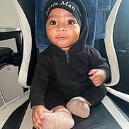 Jaxxon joined the competition — help win amazing prizes! baby, child, hoodie, black_clothing, beanie, socks, chair, indoor, cute, curious, person, portrait, seated, baby_face, infant, black_and_white_chair, small_hands, wide_eyes, casual_clothing, home