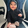 baby, child, smiling, black_hoodie, beanie, little_man, socks, chair, indoor, cute, portrait, happy, seated, furniture, person, infant, cozy, black_clothing, headwear, expression